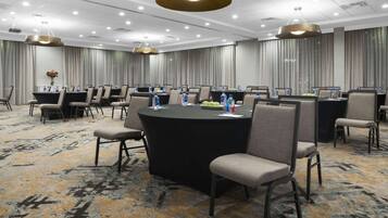 A conference room with a large round table, multiple chairs, and a carpeted floor.