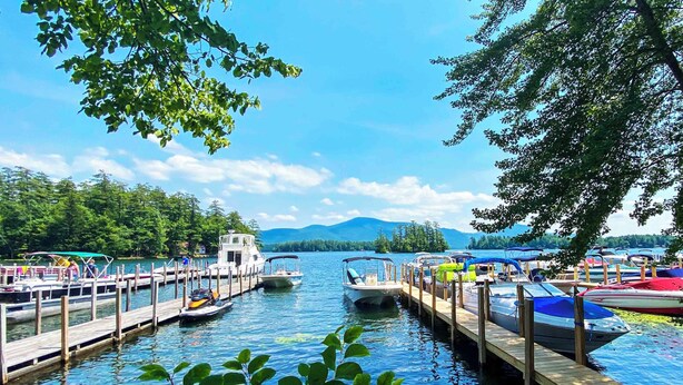 A docked boat marina with wooden piers, calm water, and a mountainous backdrop. - Lakeview Suites (Bolton Landing)