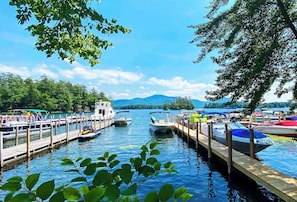 A docked boat marina with wooden piers, calm water, and a mountainous backdrop. - Lakeview Suites (Bolton Landing)