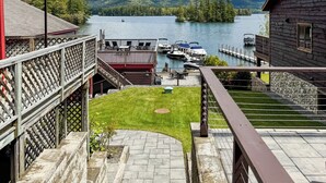 A lakeside property with a wooden deck, a boat dock, and a view of the lake and mountains. - Lakeview Suites (Bolton Landing)