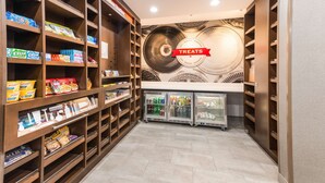 A well-organized snack and beverage area with shelves stocked with various snacks and drinks, and a sign indicating the section.