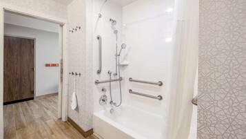 A modern bathroom with a walk-in shower, grab bars, and a white bathtub.