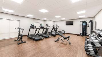 A gym with treadmills, elliptical machines, and weight benches.