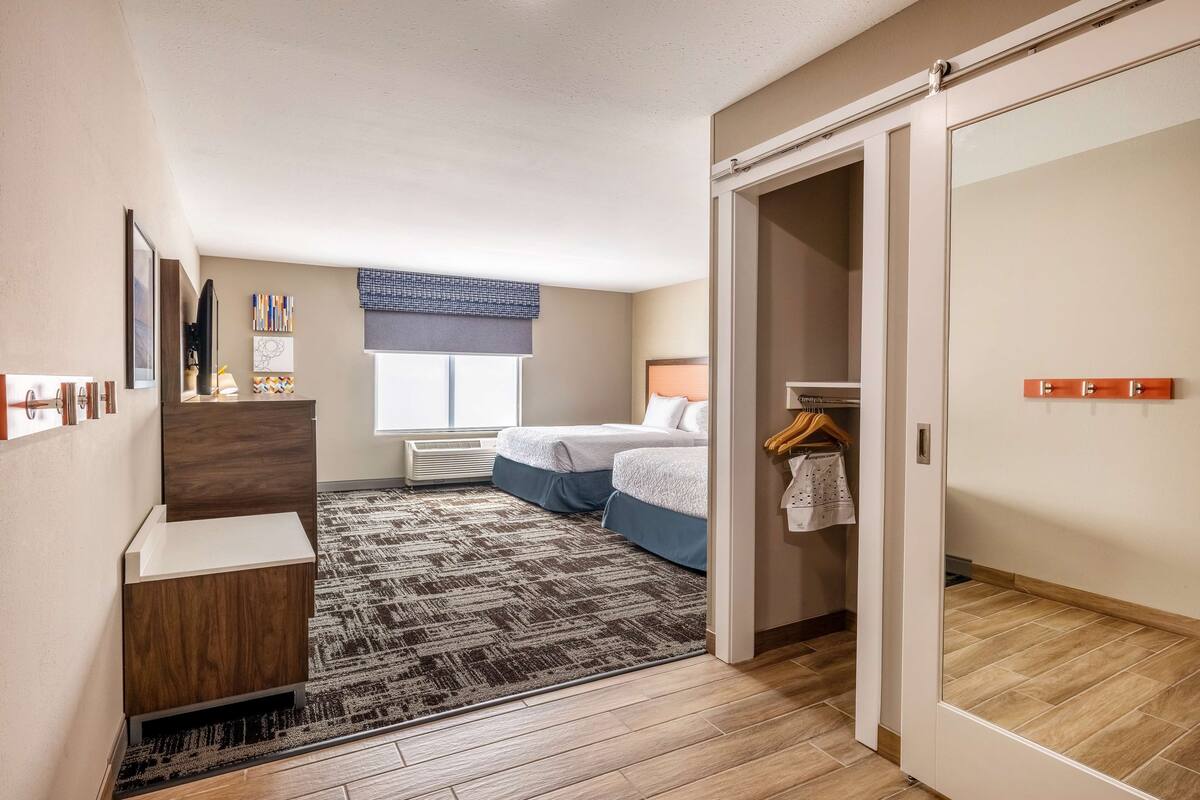A hotel room with a bed, a desk, a wardrobe, and a window.