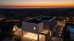 Una casa moderna de dos pisos con techo plano y un pequeño balcón.