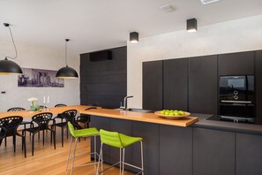 A modern kitchen with a wooden island, black bar stools, and a Bosch oven.