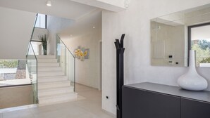Un interior moderno con una escalera, un espejo grande y un elegante mueble consola minimalista.