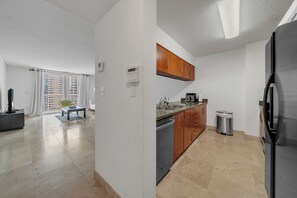 A modern kitchen with a dishwasher, stainless steel sink, and a refrigerator.