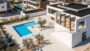 Un complesso residenziale moderno con piscina, area salotto esterna e terrazza sul tetto.