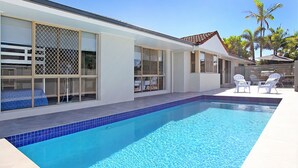 A modern house with a swimming pool, large windows, and outdoor seating.
