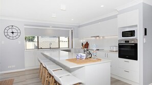 Enjoy cooking in this well-equipped kitchen with a central island, stainless steel appliances, and a large window offering a view of the outside.