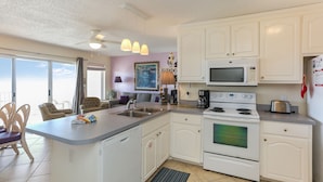 A kitchen with white cabinets, a microwave, stove, and a large island with a sink. - Beach front, updated townhome in Indian Pass~ Pelican Landing 2 (Indian Pass)