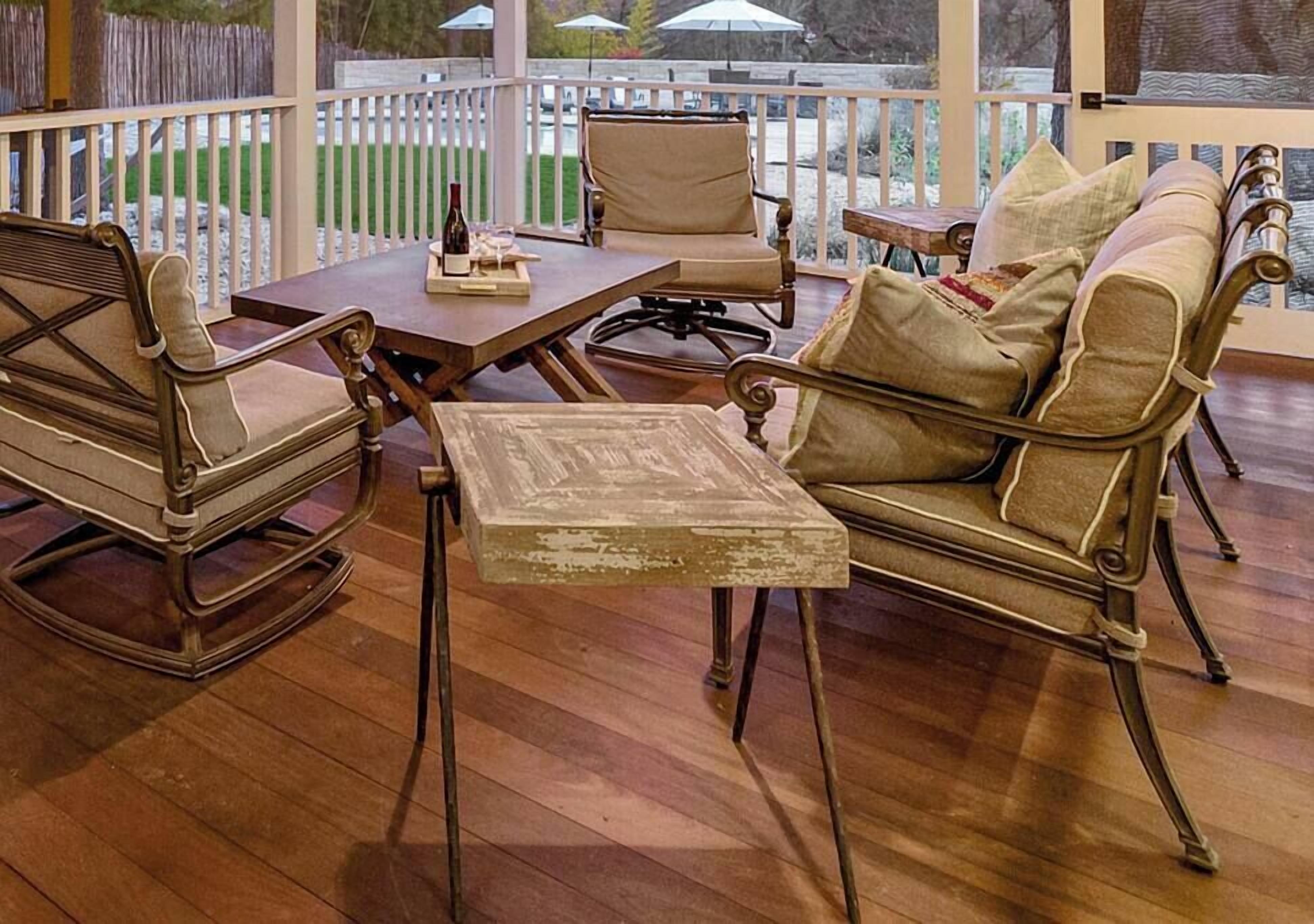 Eine Holzterrasse mit Gartenmöbeln, darunter eine Sitzecke, Stühle und ein Tisch.