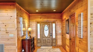 Un couloir intérieur aux murs en bois, agrémenté d’un tapis à motifs, d’une porte en bois dotée de panneaux de verre et d’une enseigne fixée au mur.