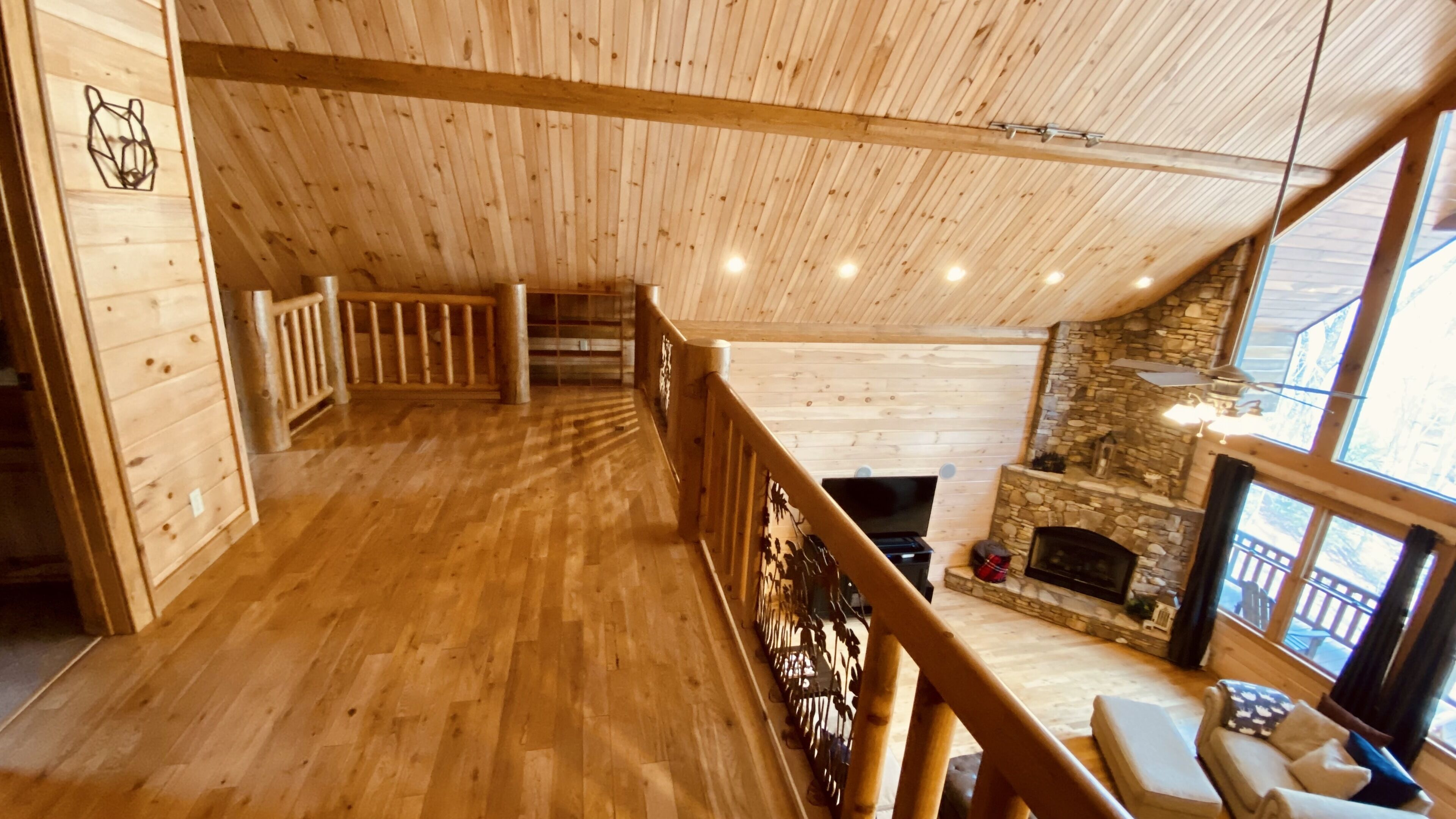 Un intérieur en bois avec une cheminée, un plancher en bois et une balustrade de balcon.