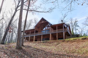 Une cabane en rondins dotée d’un balcon, entourée d’arbres.