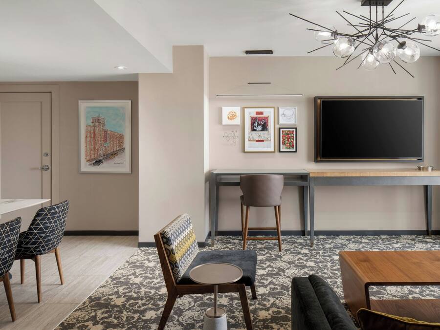 A modern room with a dining area, a sofa, a TV, and a patterned carpet.