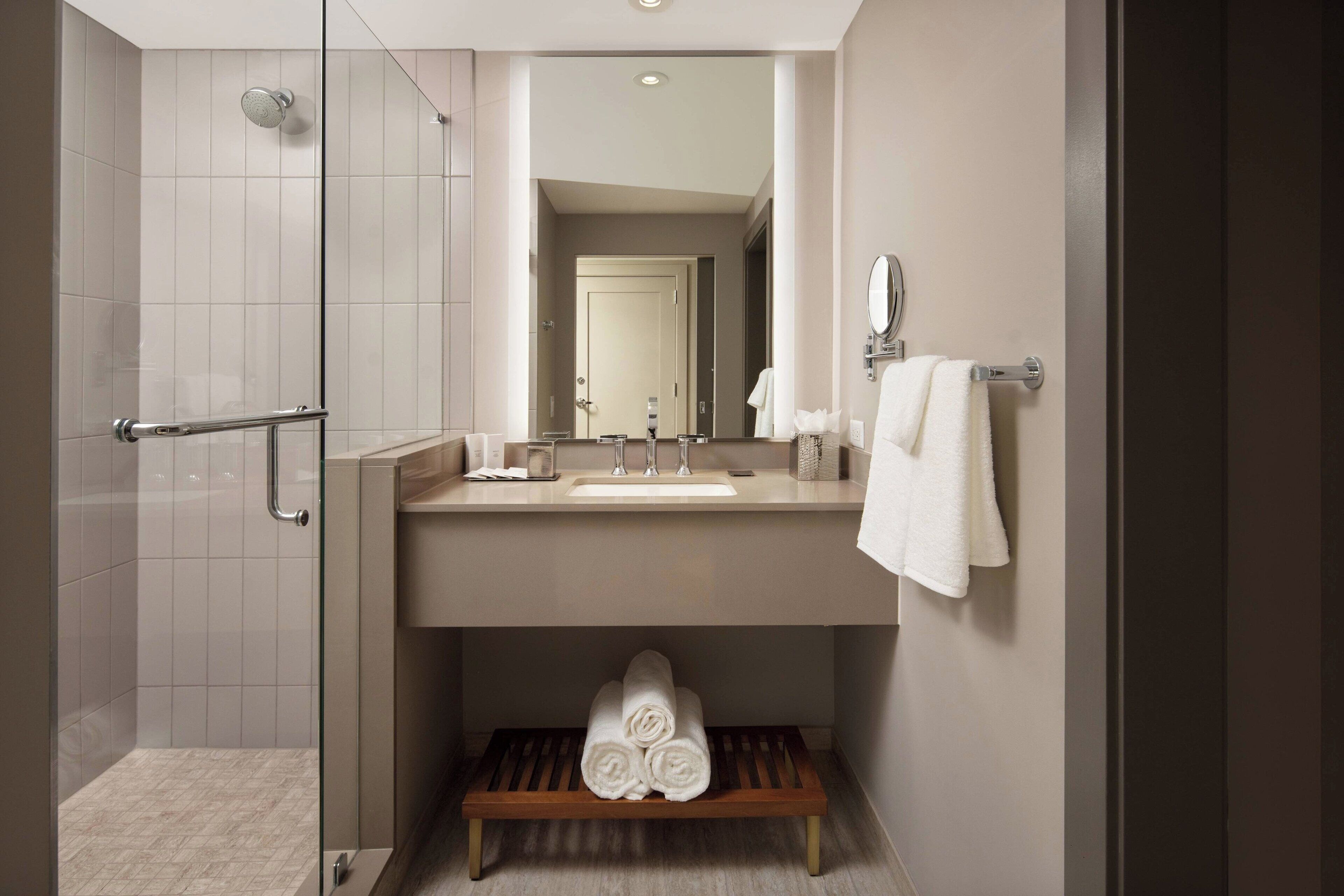 A modern bathroom with a glass shower enclosure, a sink with a mirror, and a towel rack.