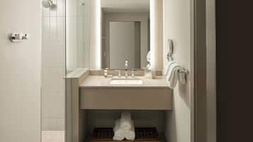 A modern bathroom with a glass shower enclosure, a sink with a mirror above it, and a towel rack with towels.