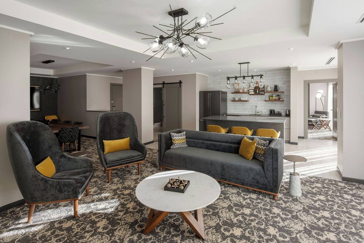 A modern living room with grey sofas, yellow cushions, and a round coffee table.
