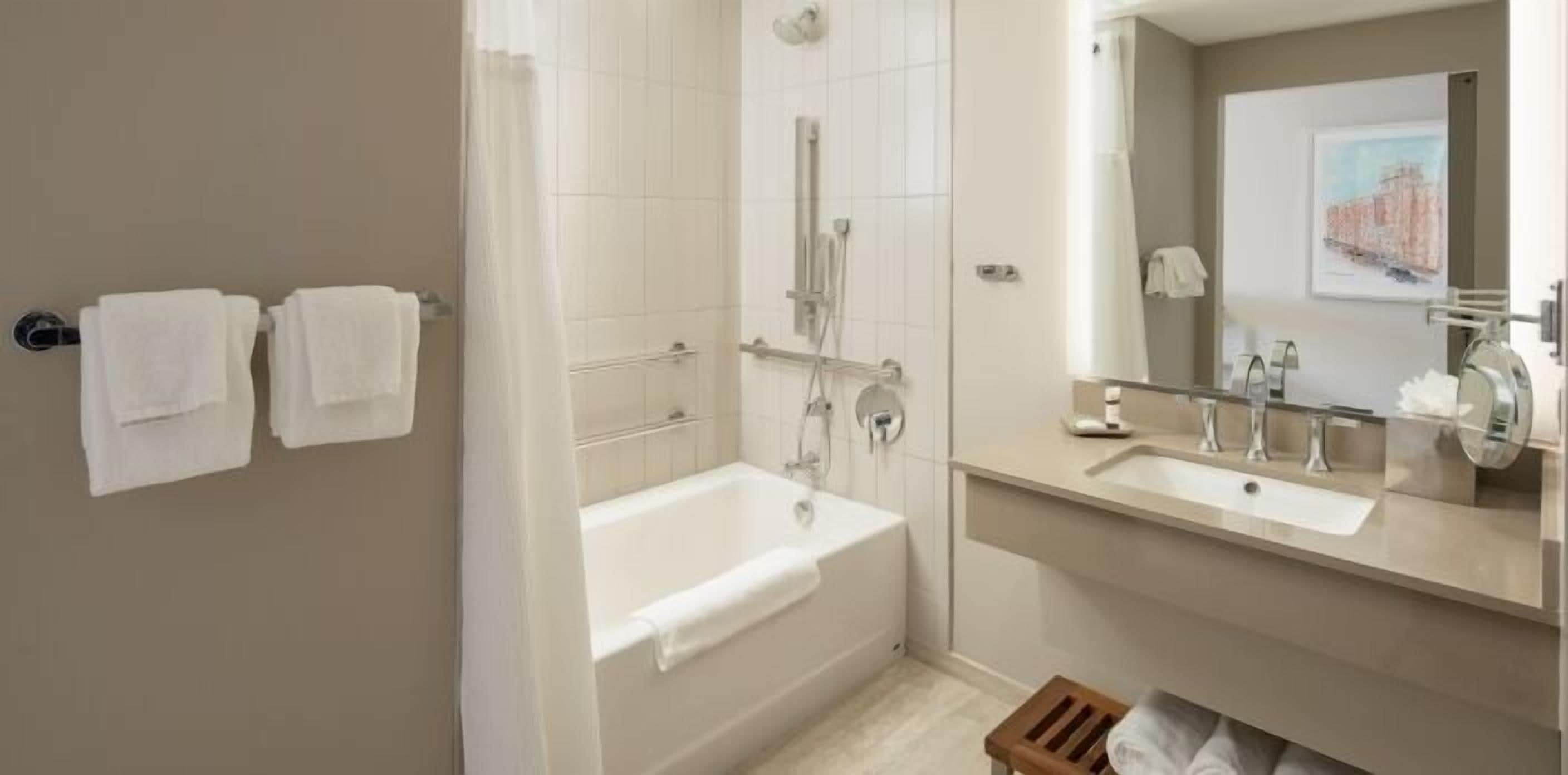 A modern bathroom with a bathtub, a shower, and a vanity with a mirror.