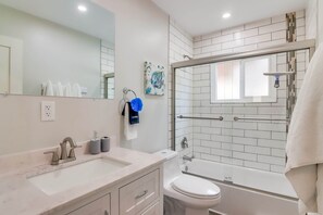 Un baño moderno con lavamanos, inodoro y ducha.