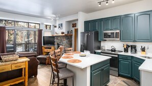 Une cuisine moderne avec des meubles de couleur turquoise, un îlot central et un coin repas comprenant un canapé et des chaises.