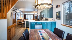 Une cuisine moderne avec des meubles de couleur turquoise, une table à manger en bois et un grand lustre.