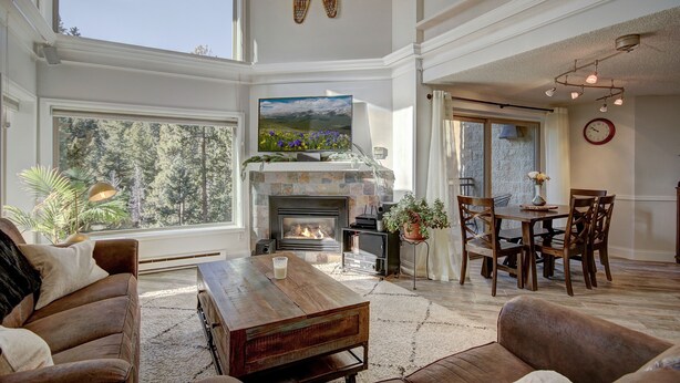 A spacious living room with a fireplace, large windows, and a dining area.
