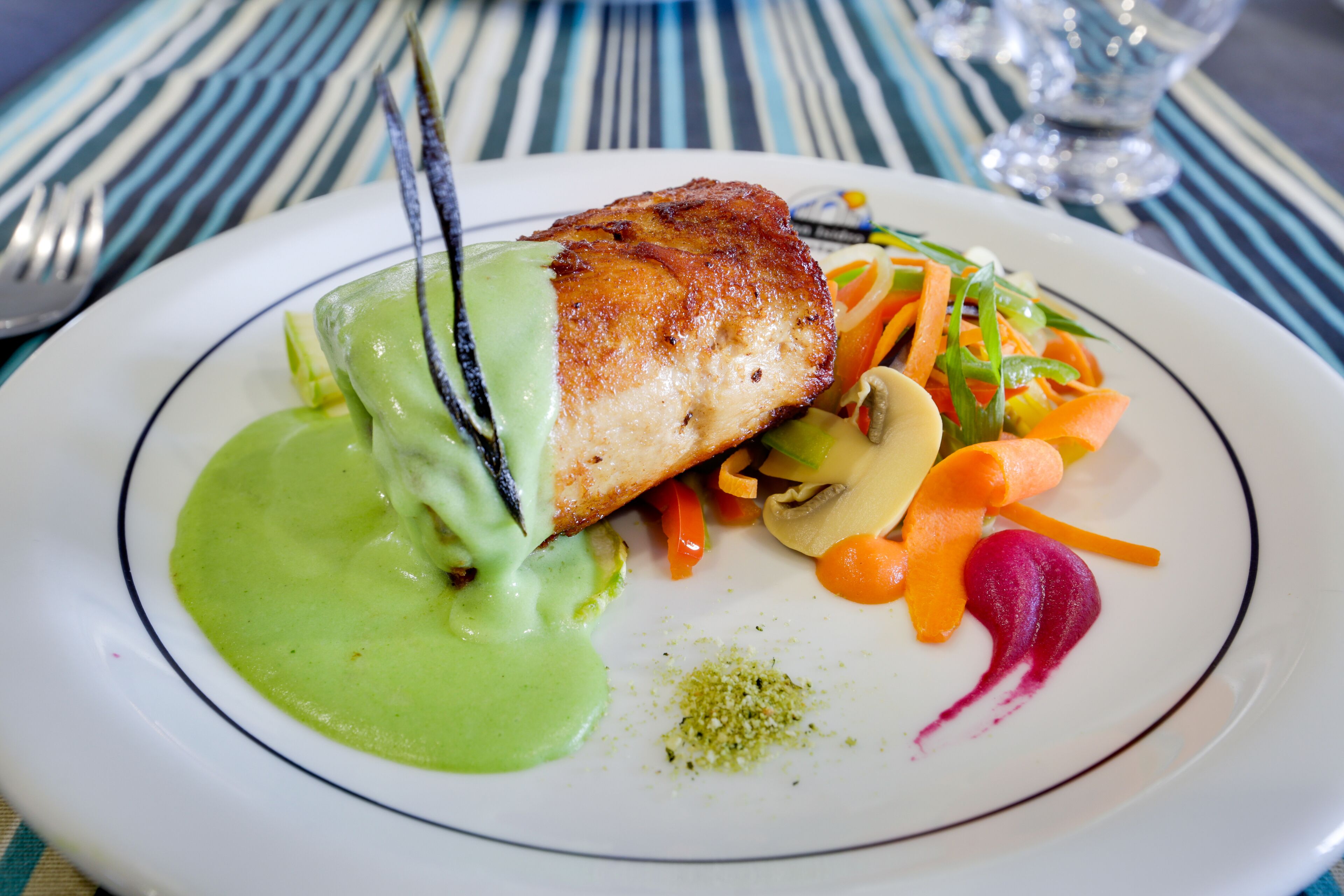 Un plato de comida con carne, verduras y salsa verde.