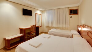 A hotel room with two beds, a desk, a chair, a TV, and a window with curtains. - Hotel San Isidro (Sao Gabriel)