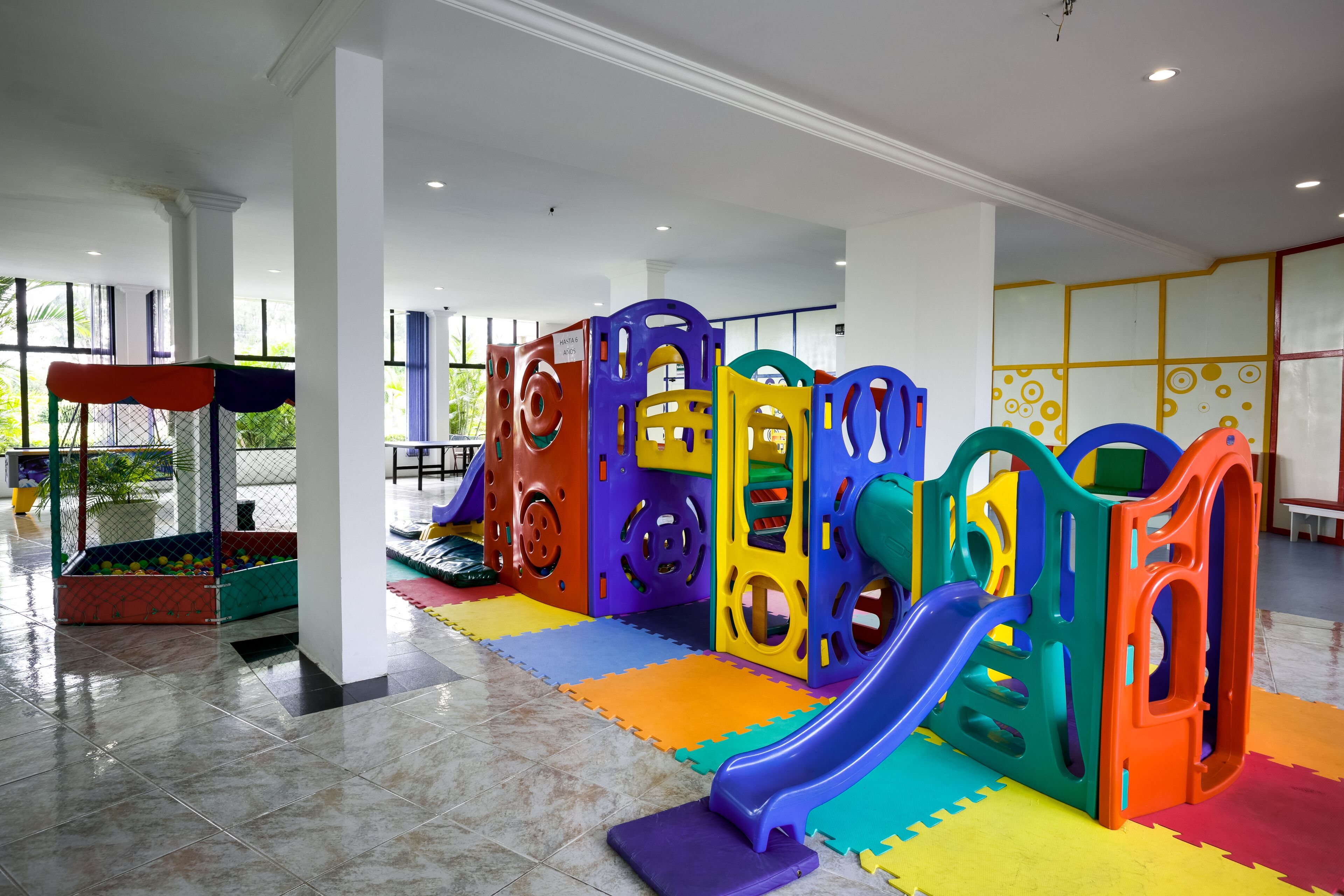 Un área de juegos infantiles con estructuras de juego coloridas y suelo acolchado.