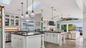 A spacious kitchen with white cabinetry, a large island, and pendant lighting. - Manasota Key Dock house - Stunning Bayfront with private beach access for the perfect vacation (Englewood)