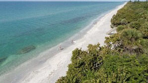 A beach with clear turquoise water, white sand, and lush greenery. - Manasota Key Dock house - Stunning Bayfront with private beach access for the perfect vacation (Englewood)
