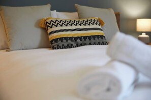 A neatly made bed with white linens and a patterned pillow. - Fermain Apartment - Spacious cosy duplex apartment - Sleeps 5 (Filey)