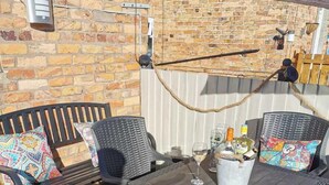 An outdoor patio with wicker furniture, a table, and a brick wall. - Fermain Apartment - Spacious cosy duplex apartment - Sleeps 5 (Filey)