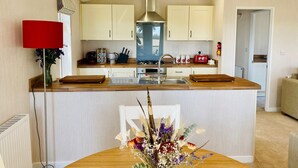 A modern kitchen with a central island, wooden countertops, and light-colored cabinetry. - Hollicarrs - Wildflower Lodge (York)