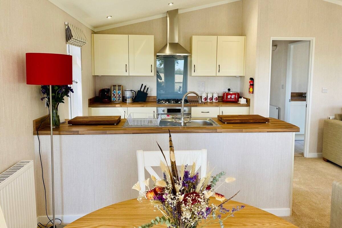 A modern kitchen with a central island, wooden countertops, and light-colored cabinetry.