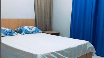 A single bed with a wooden headboard, a nightstand, and a blue curtain.