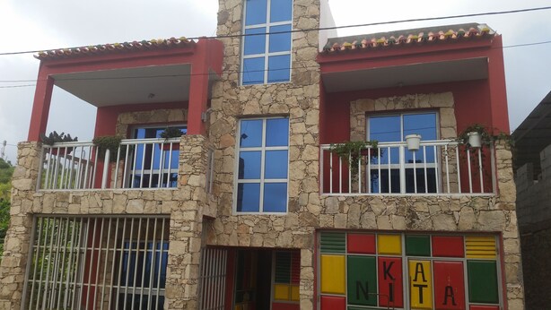 Un edificio de varios pisos con fachada de piedra, balcones con barandillas y ventanas con contraventanas de colores.