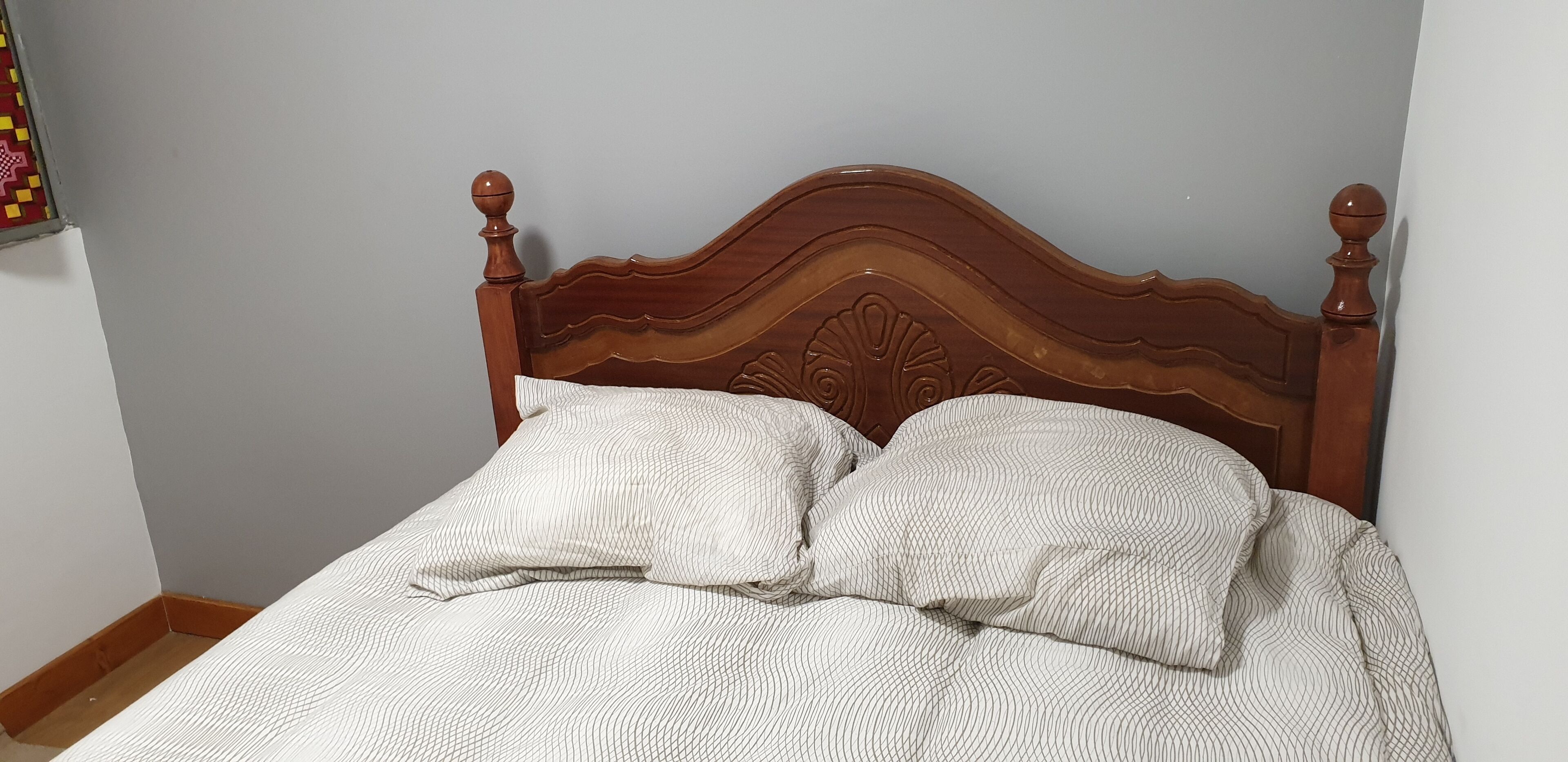 Una cama con cabecera de madera y dos almohadas.