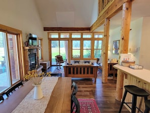 Enjoy a spacious room with a high ceiling, dining area, and comfortable seating by the fireplace.