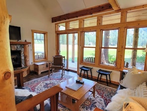 Cozy room with a stone fireplace, comfortable seating area, and a large window offering a view of the outdoors.