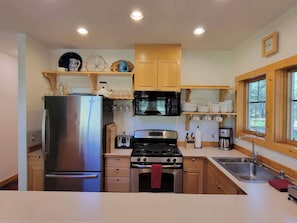 Enjoy cooking in this well-equipped kitchen with a refrigerator, microwave, toaster, and oven, plus a sink and window.