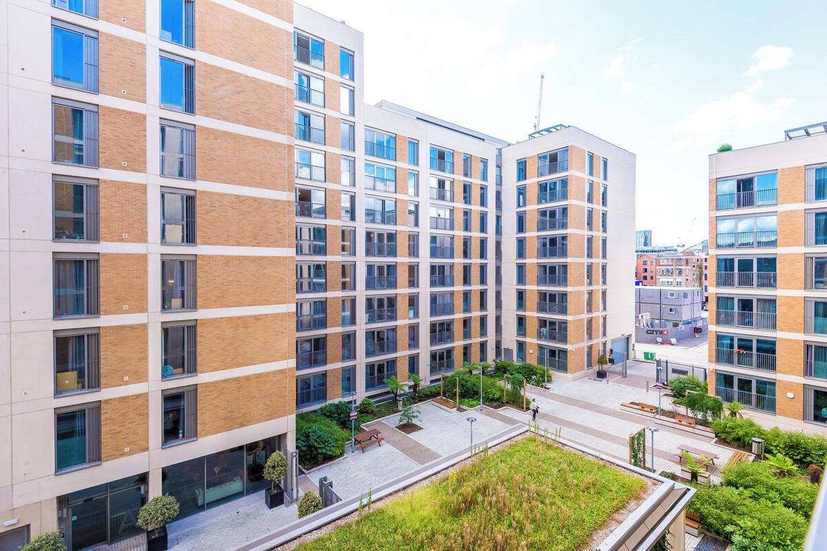 A modern multi-story building with a courtyard featuring outdoor seating and greenery.