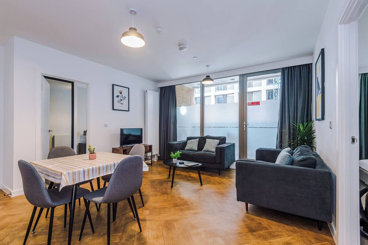 A modern living room with a sofa, a dining table with chairs, a coffee table, and a TV.