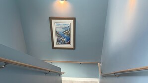 A staircase with a handrail, a picture on the wall, and a light fixture above. - Traverse City, West side of downtown, Sleeps 6, Slabtown area (Traverse City)