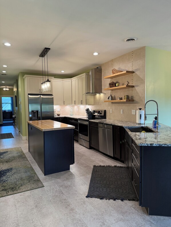 A modern kitchen with a central island, stainless steel appliances, and built-in cabinetry.