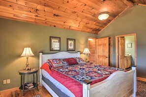 Un dormitorio con techo de madera, una cama con colcha, dos lámparas de noche y puertas de madera.