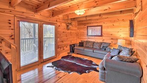 Ein Interieur einer Holzhütte mit einer Couch, einem Teppich und einem aufgehängten Hirschkopf.